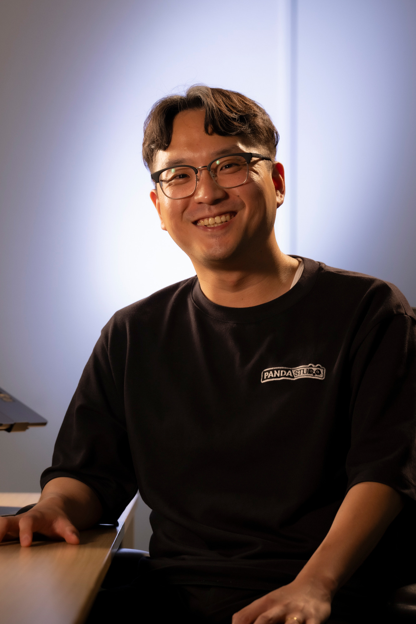 スタジオのデスクで笑顔を見せる李正遠さん