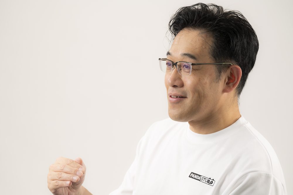 手を上げて話す藤本秀基さん