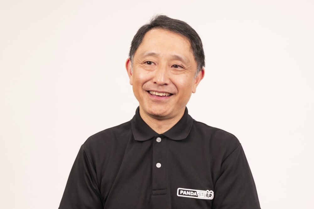 白い背景の前で、こちらを向いて笑う芥田雄輝さん